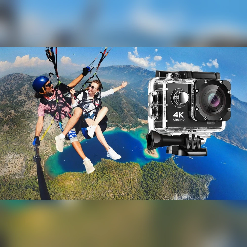 Tandem paragliders above a coastal landscape beside a large view of an action camera in a clear housing.